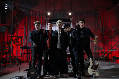 2Z Group Photo: 5 men wearing black jackets standing looking into the camera. 2 of them are holding their guitars upright.